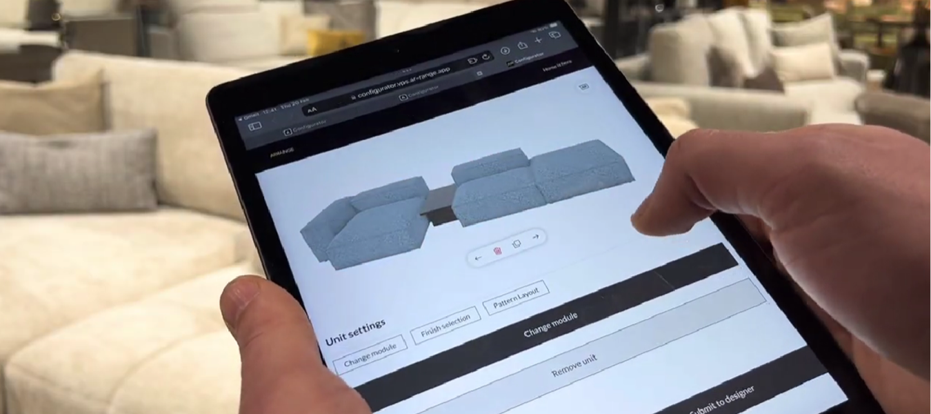 A person holds a tablet in a furniture store, using an online 3D configurator to customize a modular sofa set